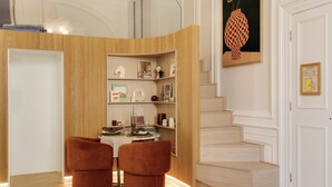 Un intérieur moderne avec un mur d’accent en bois, un coin repas avec deux chaises, un escalier et une œuvre d’art encadrée au-dessus de la porte.