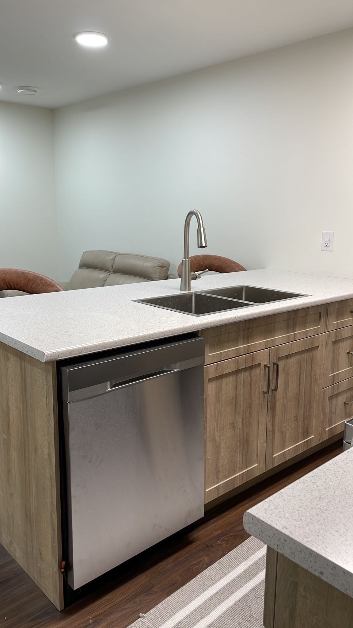 A modern kitchen with a dishwasher, a sink, and wooden cabinets.