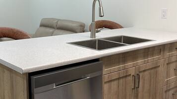 A modern kitchen with a dishwasher, a sink, and wooden cabinets.