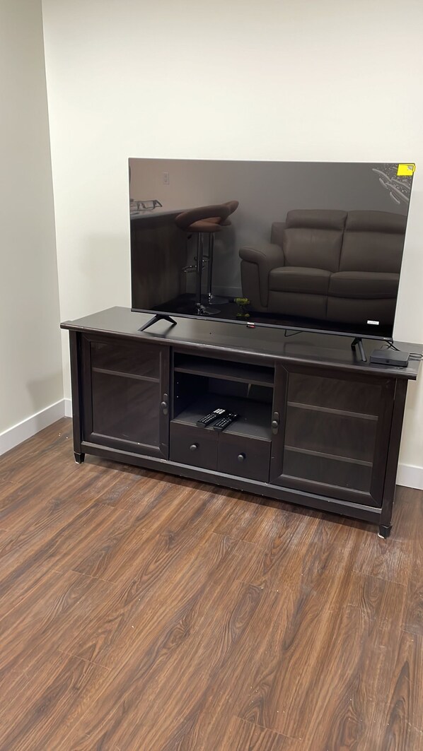 A dark wood floor, a black entertainment center with a flat-screen TV, and a brown leather sofa. - Two Bedroom House (Basement suite) with private entrance. (Edmonton)