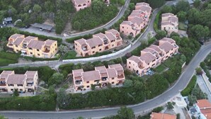An aerial view of a residential area with terraced houses, narrow roads, and surrounding greenery. - Villa Aurea Snow White 139 (Costa Rei)