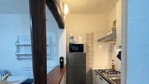 A narrow kitchen with a wooden counter, a refrigerator, a microwave, and a stove.