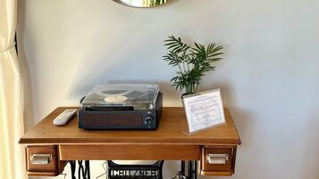 A wooden desk with a vintage sewing machine, a turntable, a remote control, and a potted plant.