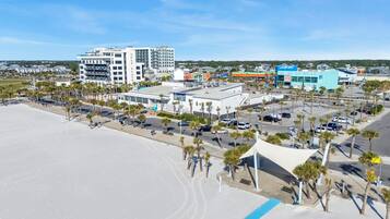 A beachfront hotel with a large building, a parking lot, and a beach area.