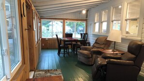 A cozy room with wooden floors, a dining table with chairs, and leather recliners.