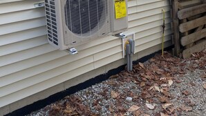 An air conditioning unit mounted on a house's exterior wall.