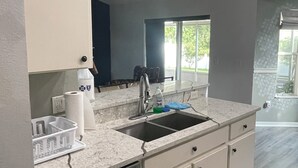 A modern kitchen with white cabinets, a double sink, and a dishwasher.