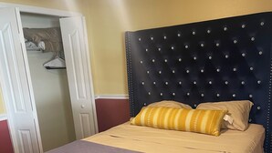 A neatly made bed with a blue and beige bedspread, a tufted headboard, and two pillows.