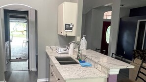 A compact kitchen with a sink, countertop, and a trash bin.