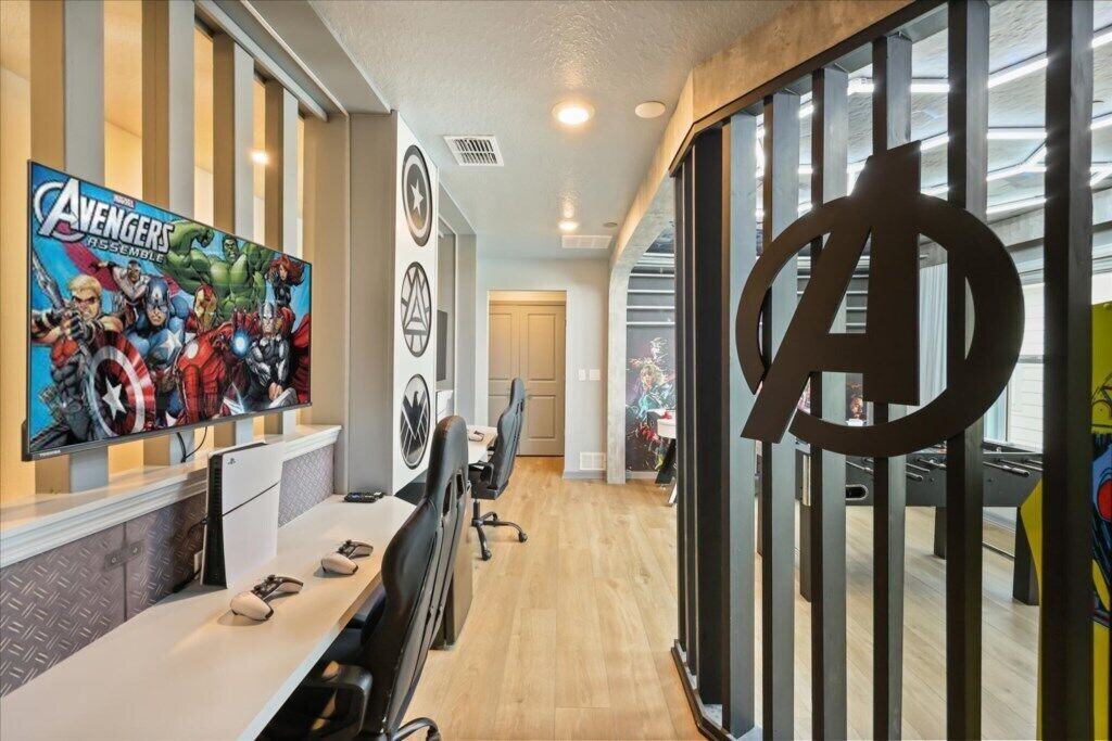 Une salle de conférence avec une grande affiche représentant les Avengers réunis, un grand logo des Avengers et une longue table entourée de chaises.