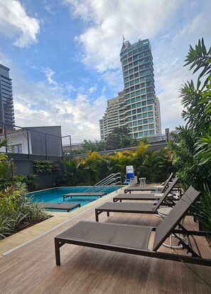 A rooftop pool area with lounge chairs and a view of a tall building. - Condominio Helbor B.liv (São Paulo)