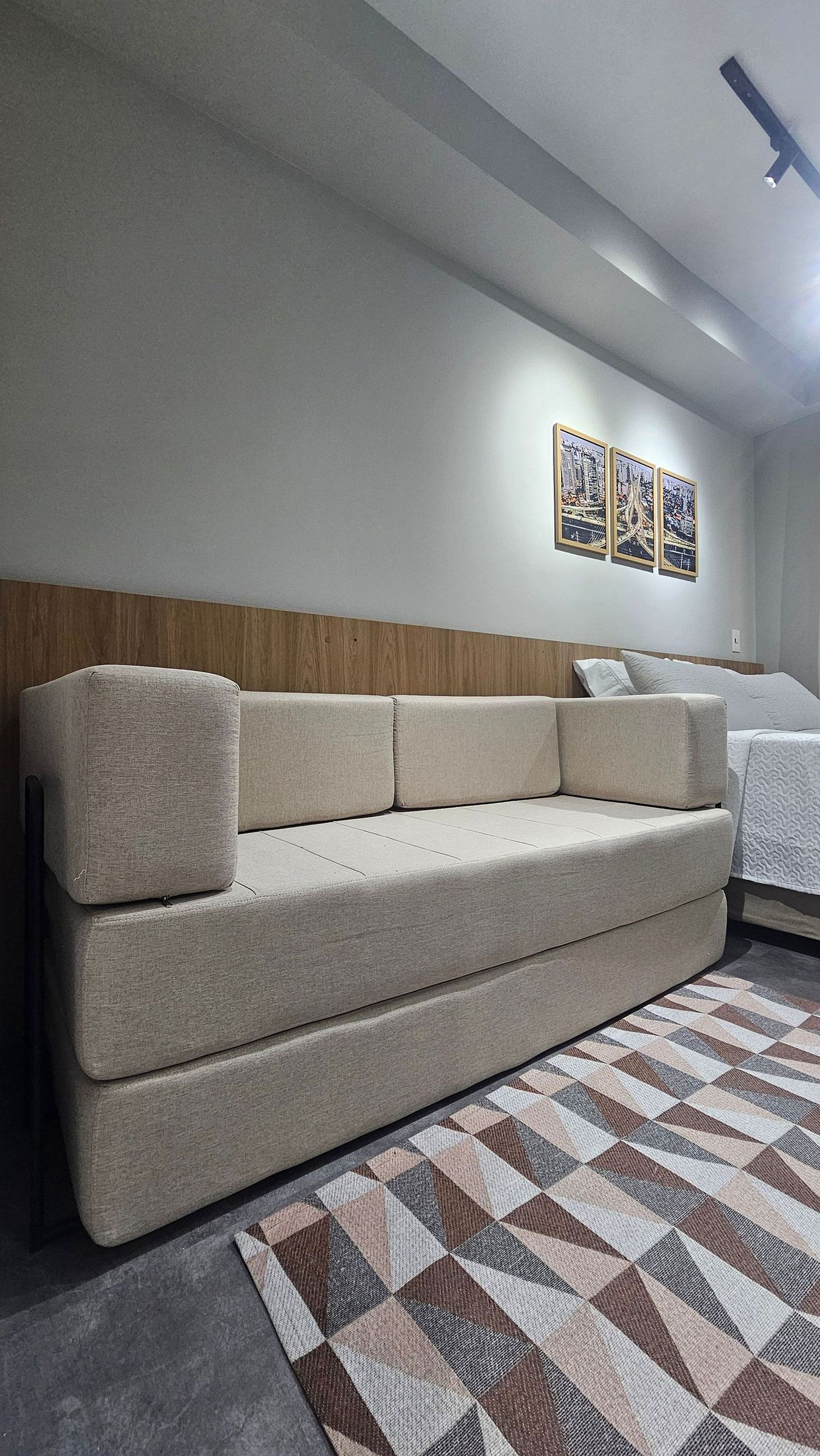 Et moderne hotelværelse med sofa, et mønstret tæppe og en seng.