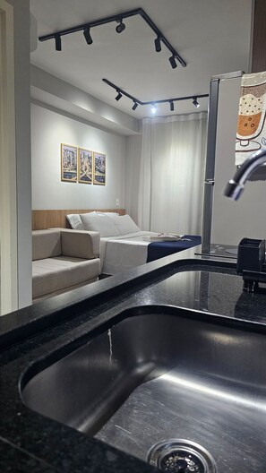 A modern bathroom with a large sink, a mirror, and a shower area. - Condominio Helbor B.liv (São Paulo)