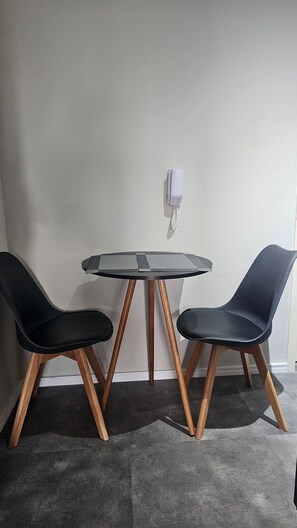 A small round table with two black chairs, a white wall, and a white electrical outlet. - Condominio Helbor B.liv (São Paulo)