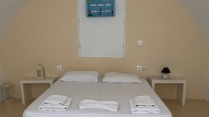 A single-bed room with a large bed, two bedside tables, a wall-mounted TV, and a small lamp. - Leon Lux Apartment, quadruple room with private bathroom. (Emporio)