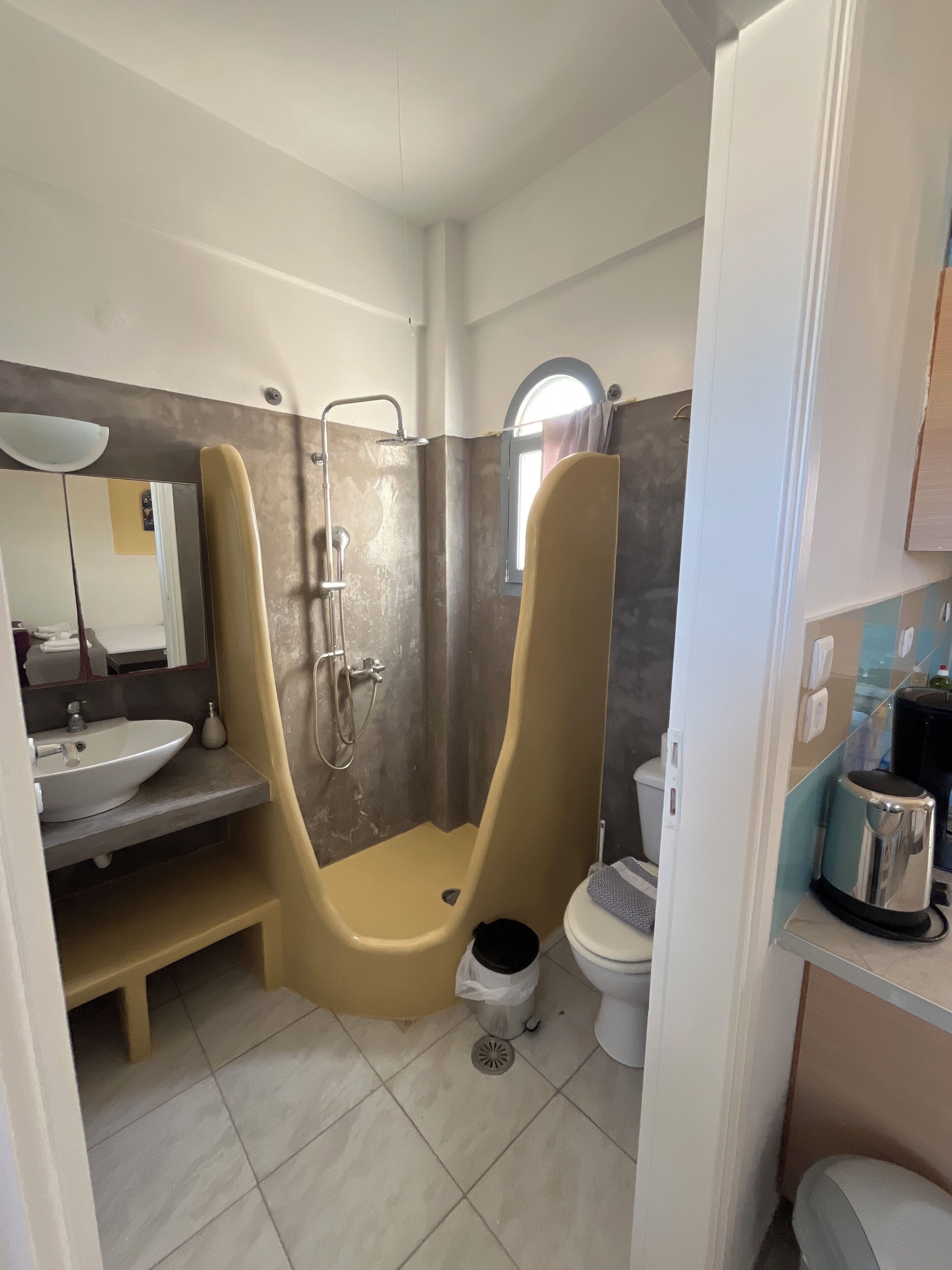 A bathroom with a shower, toilet, sink, and a mirror.