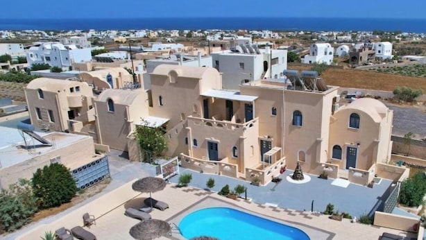 A rooftop pool area with lounge chairs and umbrellas, surrounded by buildings with Mediterranean architecture. - Leon Lux Apartment, quadruple room with private bathroom. (Emporio)