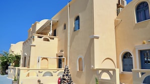 A building with a beige facade, arched windows, and a circular stone structure in the courtyard. - Leon Lux Apartment, quadruple room with private bathroom. (Emporio)