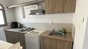 A compact kitchenette with a refrigerator, a coffee maker, a kettle, and a sink. - Leon Lux Apartment, quadruple room with private bathroom. (Emporio)