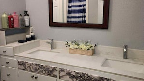 A bathroom with a double sink, a mirror, and cabinets. - Studio Near Disney (Santa Ana)