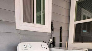 A laundry area with a front-loading washer and dryer, a window, and a door. - Studio Near Disney (Santa Ana)