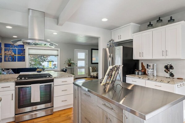 A modern kitchen with stainless steel appliances, white cabinetry, and a large island.