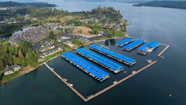 An aerial view of a lakeside rental property with multiple docked boats, a marina, and residential buildings. - The Bear's Den - Dover ID (Dover)