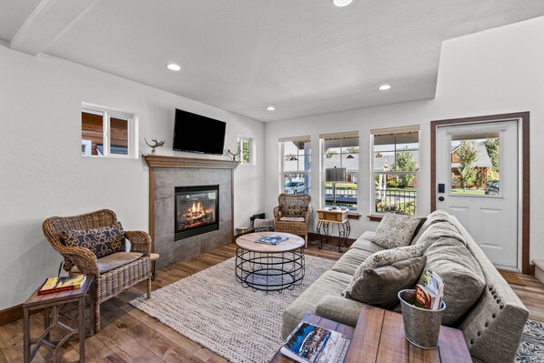 A living room with a fireplace, wicker furniture, a sofa, and a television. - The Bear's Den - Dover ID (Dover)