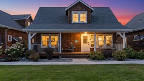 A two-story wooden house with a covered porch, a front door, and a small front yard. - The Bear's Den - Dover ID (Dover)