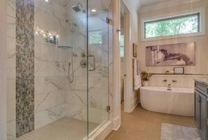 Ein modernes Badezimmer mit einer Duschkabine, einer freistehenden Badewanne und einem Marmorboden.