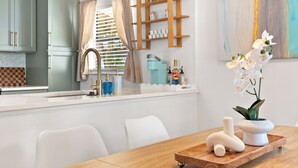 Eine moderne Küche mit weißen Schränken, einem Holztisch und einem weißen Stuhl.