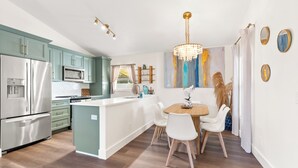 Une cuisine moderne avec des meubles de couleur turquoise, des appareils en acier inoxydable et un îlot central doté de chaises.