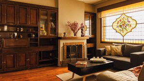Una sala acogedora con chimenea, armarios de madera y un amplio ventanal de vitral.
