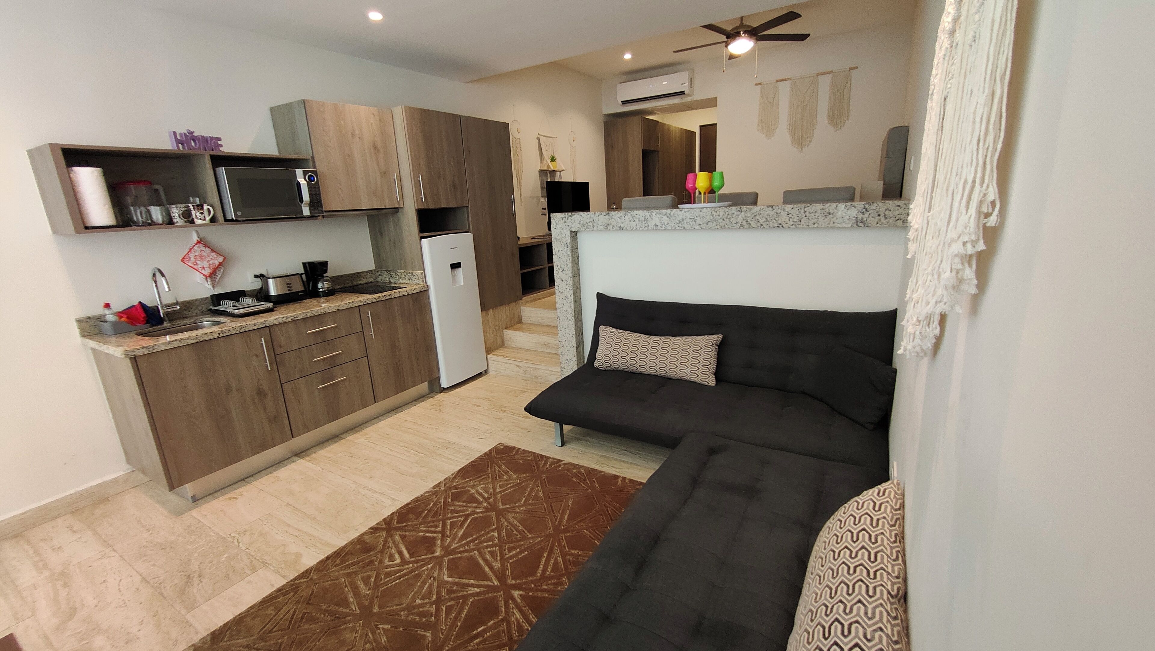 A compact living space with a kitchenette, a sofa, and a patterned rug.