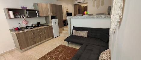 A compact living space with a kitchenette, a sofa, and a patterned rug.