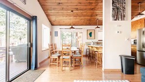 Un comedor amplio con sillas de madera y una mesa grande, una cocina con electrodomésticos modernos y vistas a una terraza exterior a través de un ventanal.