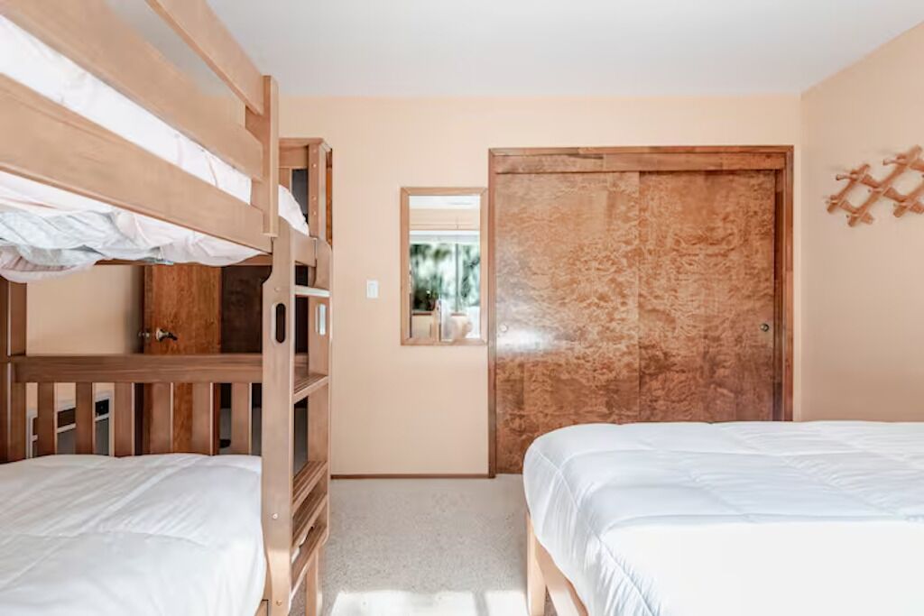 Een slaapkamer met stapelbedden, een garderobe en een deur met spiegel.