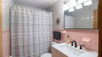 A bathroom with a striped shower curtain, a white toilet, a sink with black faucets, and a mirror above the sink.