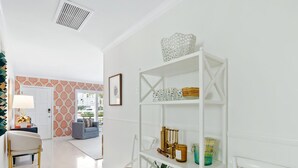Un salon moderne avec une bibliothèque blanche, un canapé gris et un coin repas comprenant une table et des chaises blanches.
