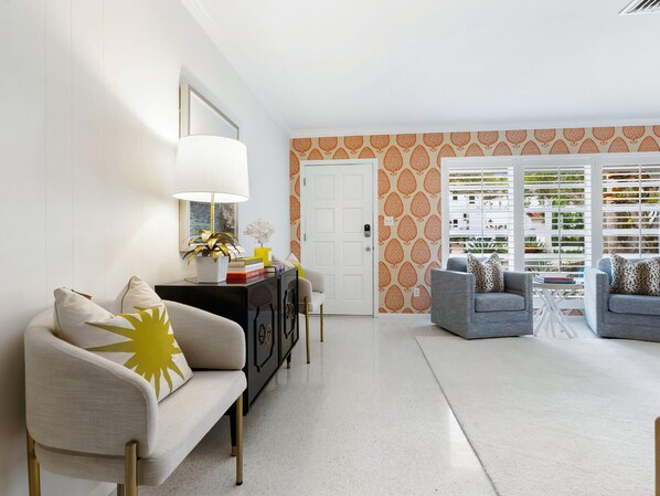 Una sala moderna con un sofá, sillones, una mesa de centro y una lámpara decorativa.
