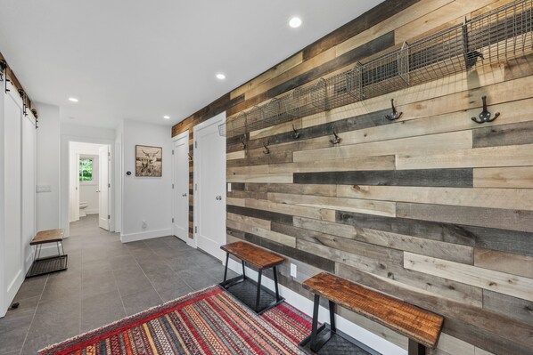 A hallway with a wooden wall, two benches, and a patterned rug.