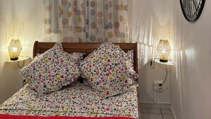 A bedroom with a bed, two bedside lamps, a wall clock, and a curtain with polka dots. - Le NID chalet classė 3*** between sea and mountains (Les Avirons)