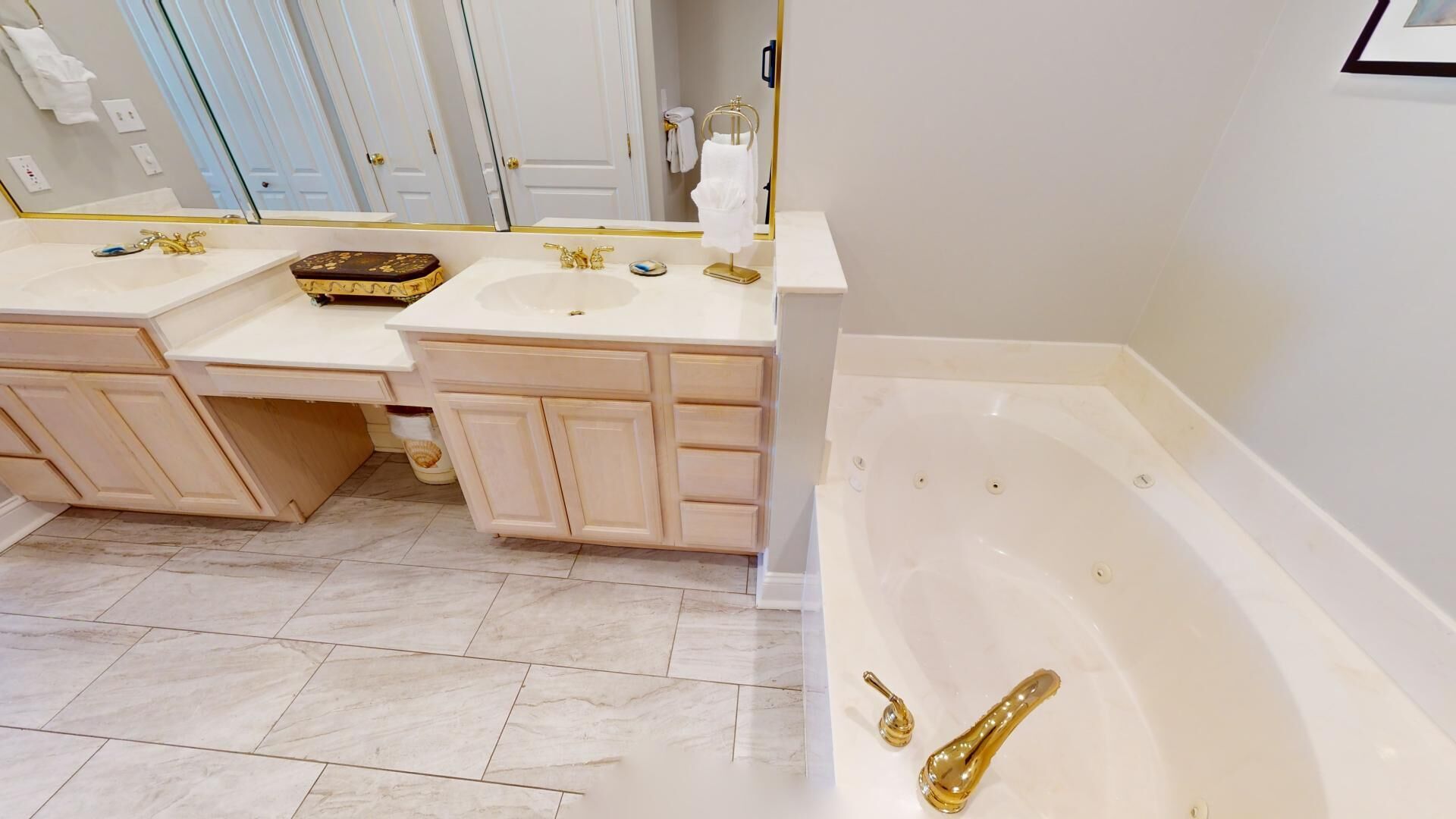 A bathroom with two sinks, a bathtub, and a vanity with cabinets.
