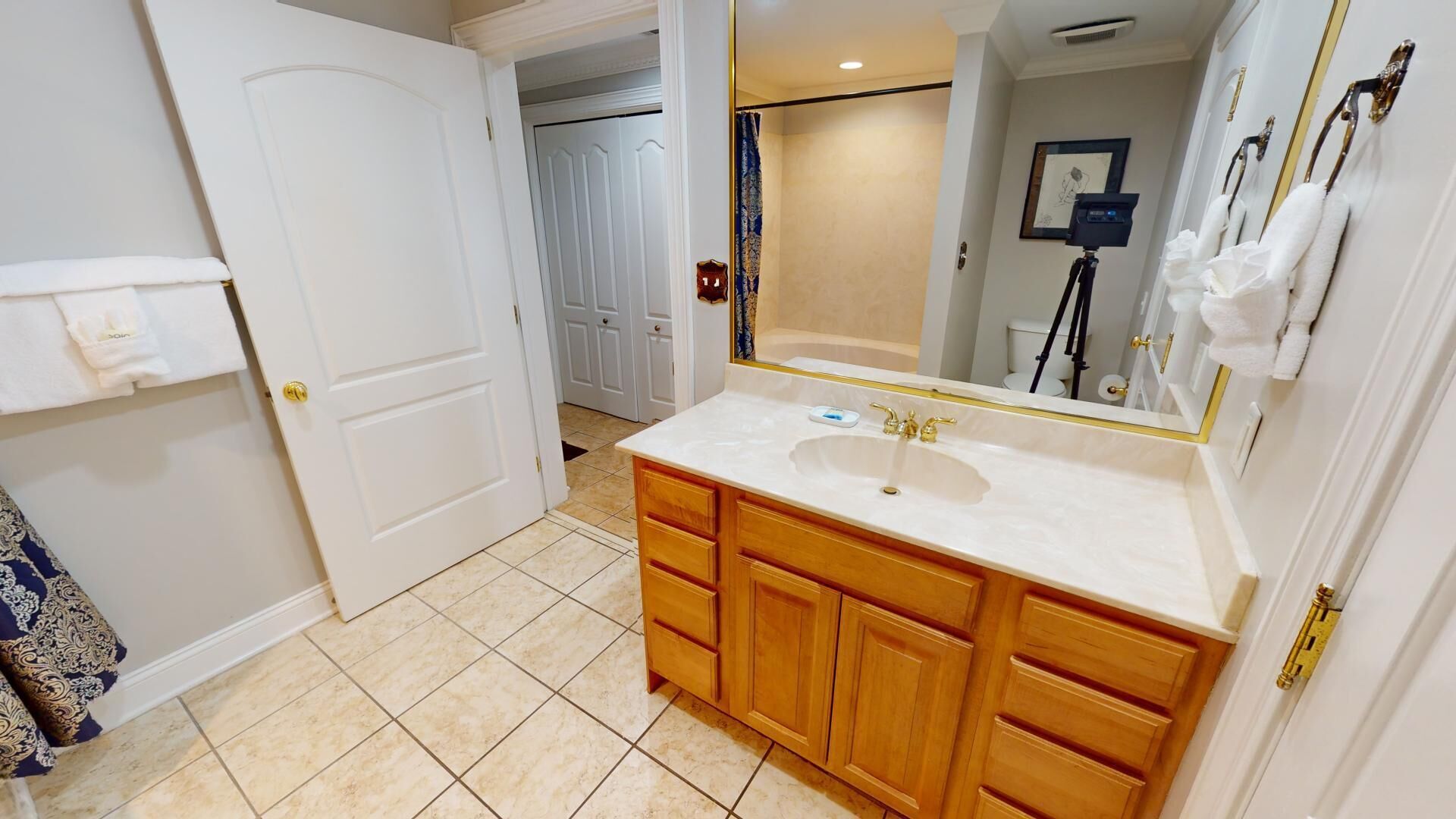 A bathroom with a white sink, wooden vanity, and a large mirror.