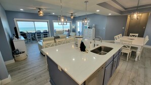 A modern kitchen with a large island, built-in appliances, and a view to the outside. - Desoto Beach Club 2 Tybee Vacation Rentals (Tybee Island)