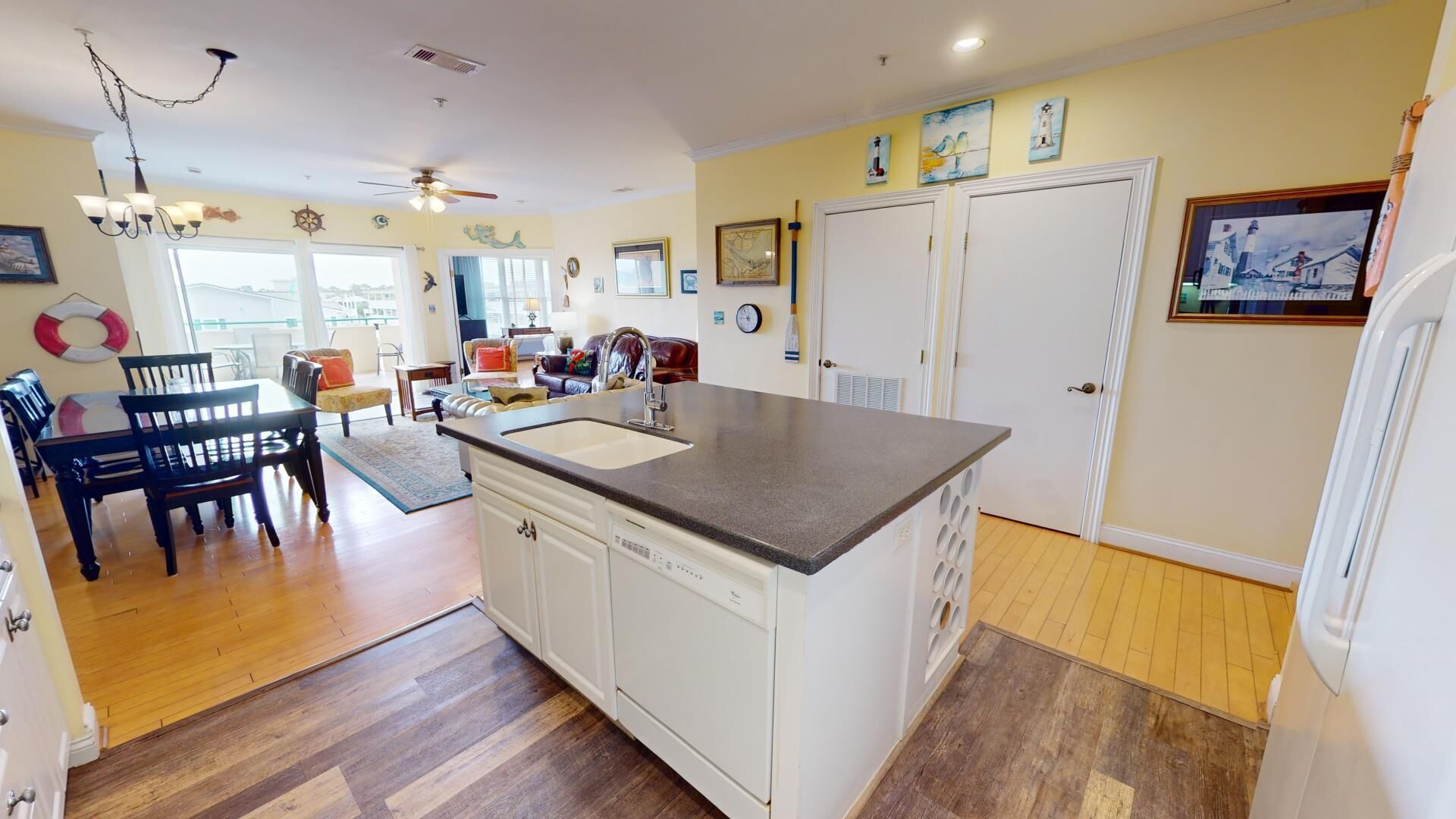 A kitchen with a central island, wooden flooring, and a dining area with chairs and a table.