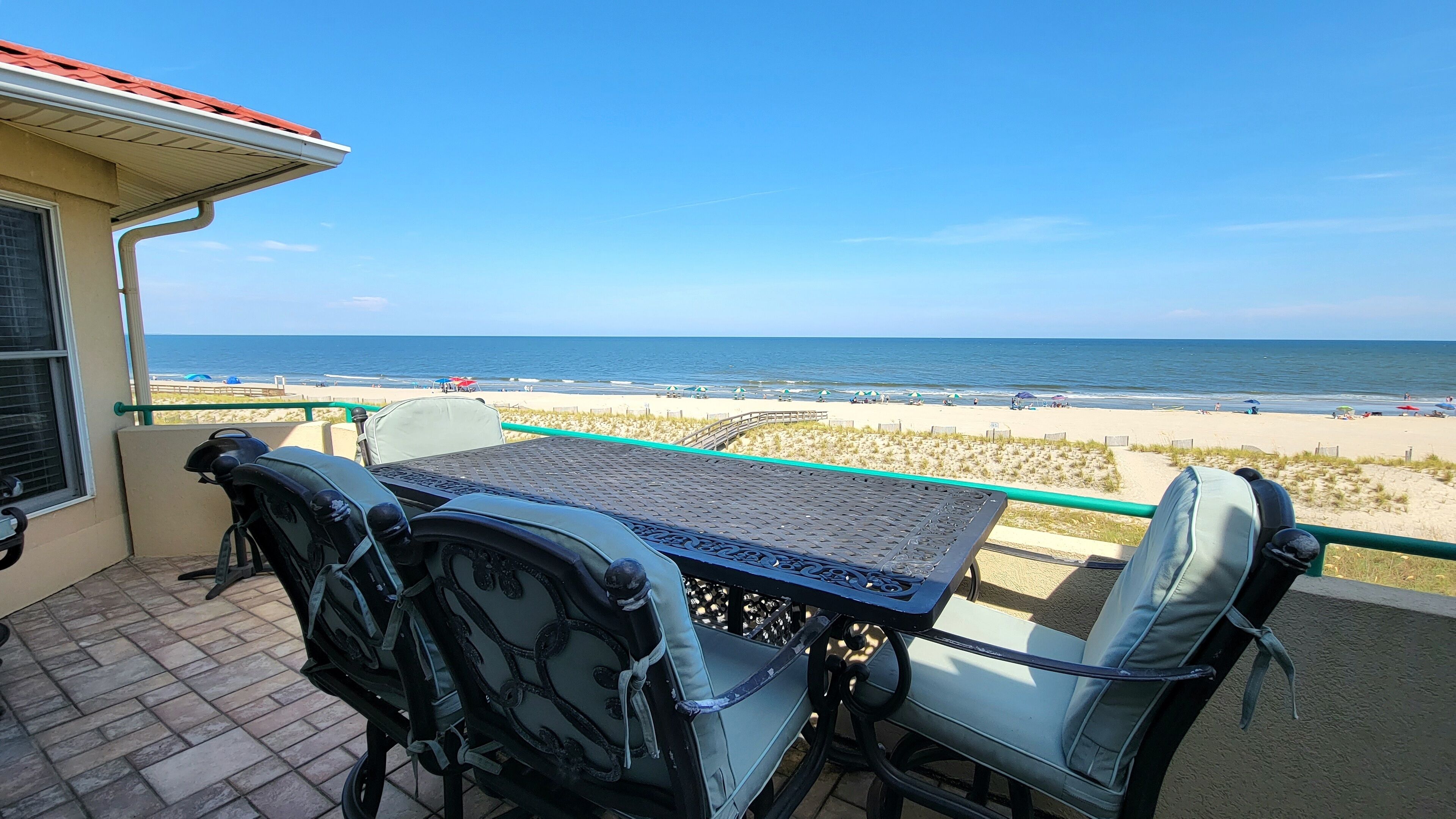 Un balcon avec une table et des chaises donnant sur une plage.