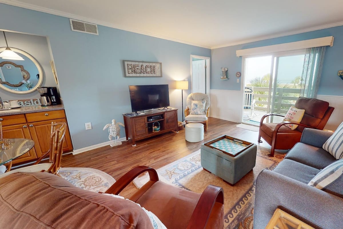 A living room with a TV, sofa, chairs, and a coffee table.