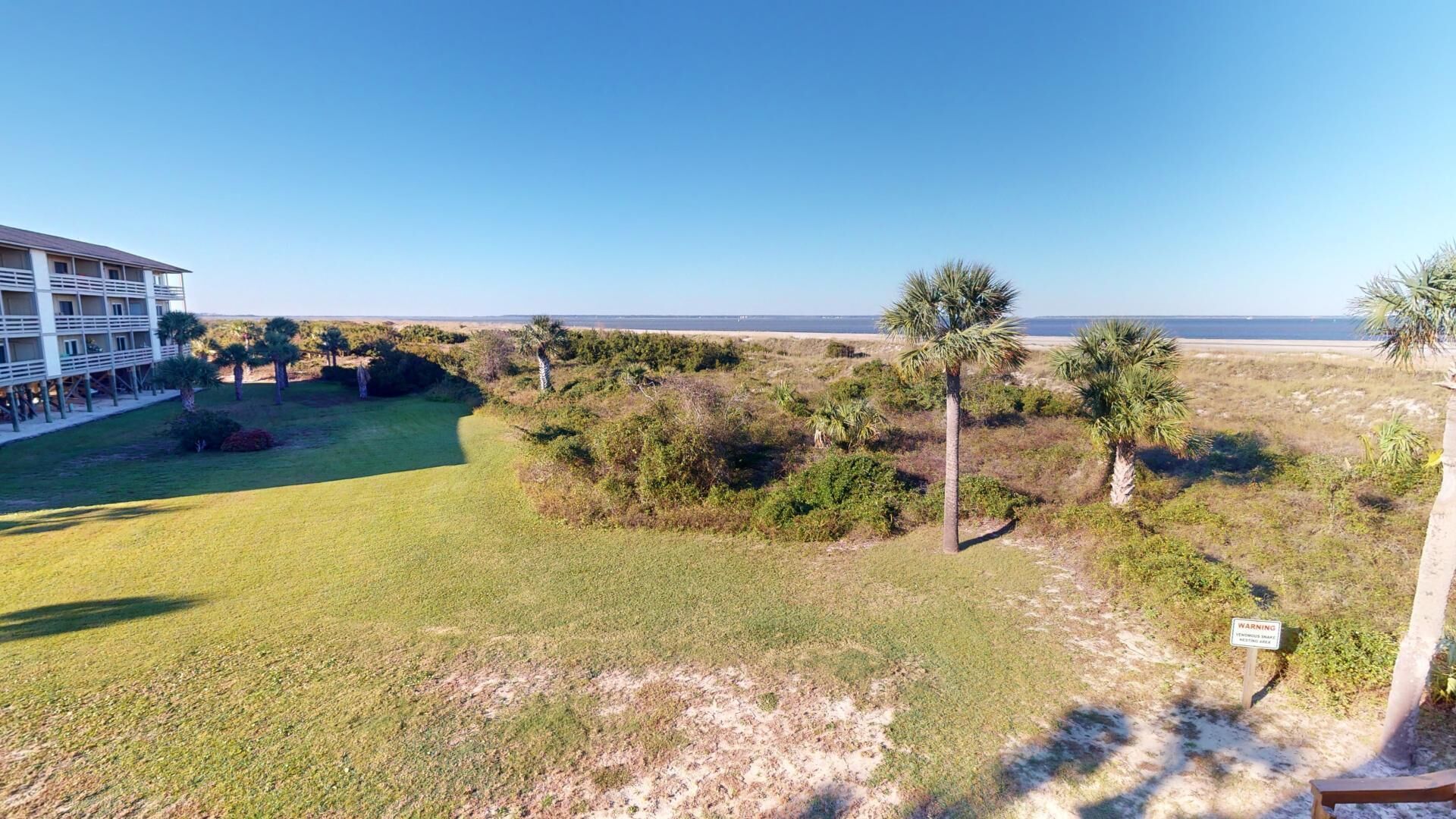 A hotel with a grassy lawn, palm trees, and a view of the beach.