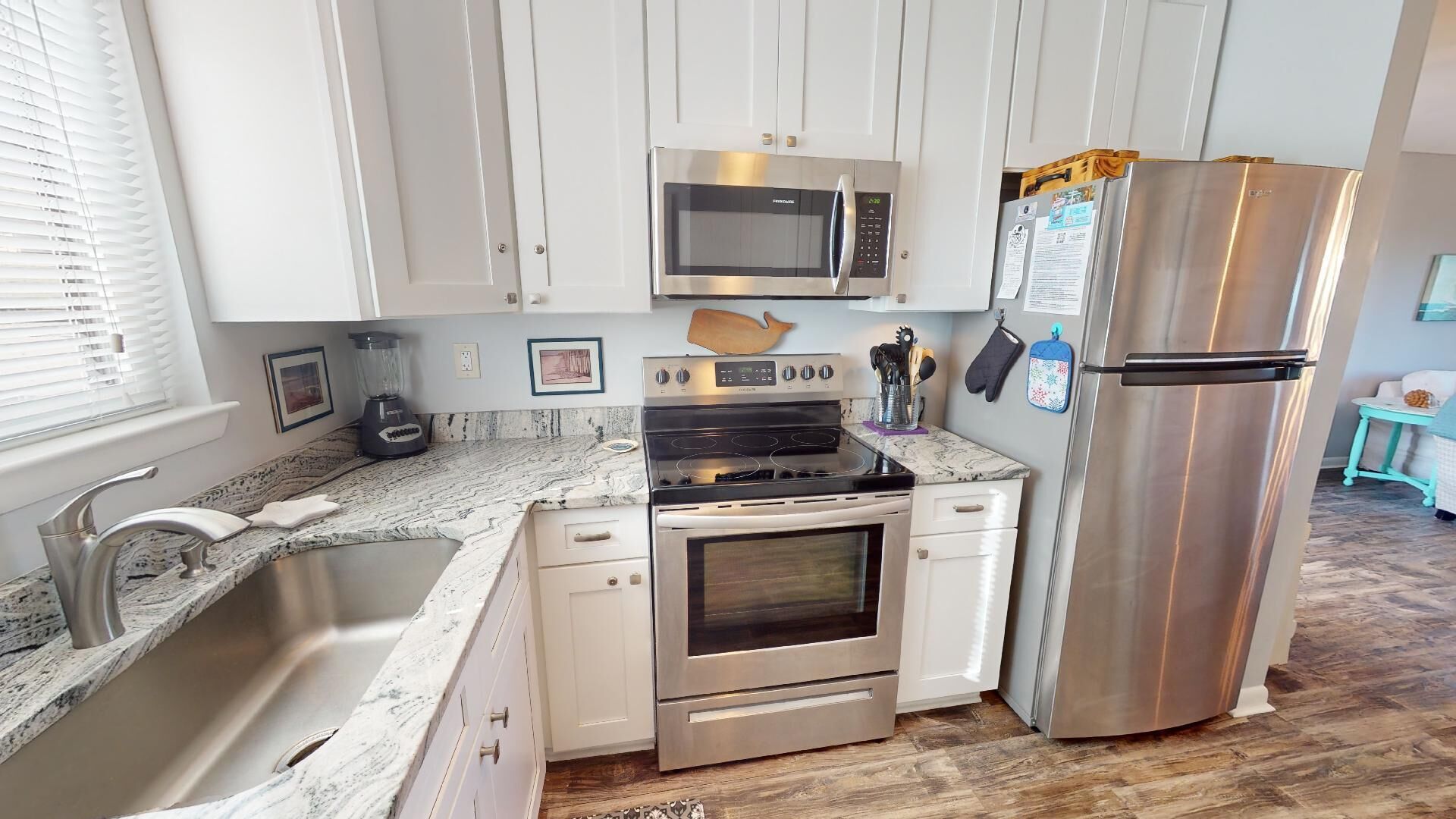 A modern kitchen with stainless steel appliances, a granite countertop, and white cabinetry.